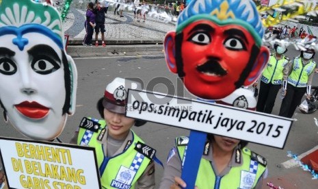 Polisi Wanita (Polwan) membawa ikon ondel-ondel saat sosialisasi operasi Simpatik Jaya 2015 di Car Free Day Bundaran HI,Jakarta, Ahad (5/4).  (Republika/Tahta Aidilla)