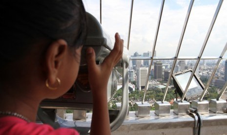 Seorang pengunjung menggunakan alat teropong menyaksikan pemandangan Ibu Kota Jakarta dari puncak Monas, Rabu (8/4).  (foto: MgROL_37)