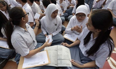    Peserta Ujian Nasional (UN)  menyempatkan diri untuk belajar saat menunggu kedatangan Presiden Joko Widodo di SMA N 2 Jakarta, Jakarta, Selasa (14/4).  (Antara/Sigid Kurniawan)