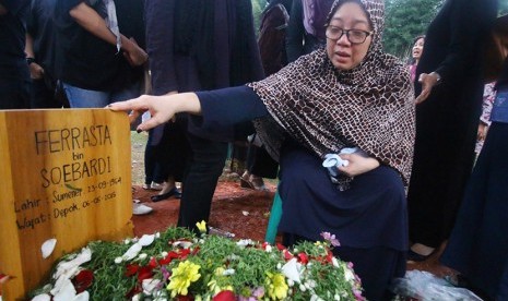 Istri Almarhum Ferrasta Soebardi atau yang akrab dipanggil Pepeng, Utami Mariam Siti Aisyah memegang pusara suaminya di TPU Jelupang, Serpong Utara, Kota Tangerang Selatan, Banten, Rabu sore (6/5). 