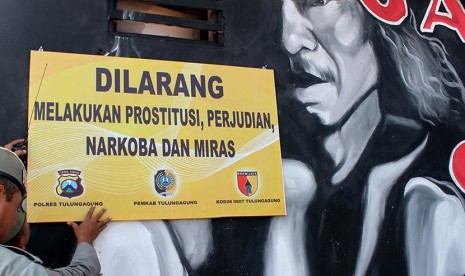  Petugas Satpol PP memasang papan pengumuman pelrangan prostitusi di kawasan eks-Lokalisasi Kaliwungu, Tulungagung, Jawa Timur, Jumat (8/5). 