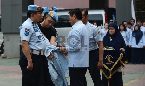  Dirjen HAM Kemenkumham, Mualimin Abdi (kanan) melepas pakaian dinas lapangan Mantan Petugas Keamanan Lapas Banceuy Dedi Romadi (tengah) saat upacara pemberhentian Lapangan Gedung Kemenkumham, Senin (1/6).  (Republika/Raisan Al Farisi)