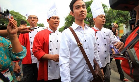 Putra sulung Presiden Joko Widodo, Gibran Rakabuming Raka (dua kanan) bersama sejumlah juru masak berjalan menuju Media Center Jokowi Mantu sebelum memberikan keterangan pers di Sumber, Solo, Jawa Tengah, Selasa (9/6).