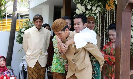   Presiden Joko Widodo (kiri) didampingi  Ibu Iriana Joko Widodo (kanan) menggendong  Gibran Rakabuming Raka (tiga kanan) saat prosesi siraman di  Solo, Jawa Tengah, Rabu (10/6).  (Antara/Maulana Surya)