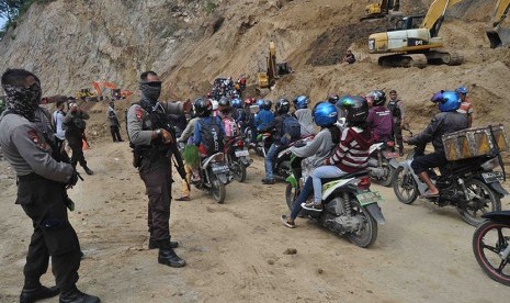  Aparat berjaga pada antrean kendaraan yang akan melintas di jalur Trans Sulawesi Desa Toboli, Parigi Utara, Kabupaten Parigi Moutong, Sulawesi Tengah, Senin (15/6).  (Antara/Patar)