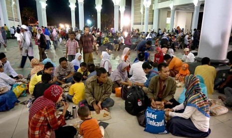 Jamaah menikmati nasi bungkus yang dibagikan usai Shalat Maghrib saat waktu buka puasa di Masjid Al Akbar Surabaya.