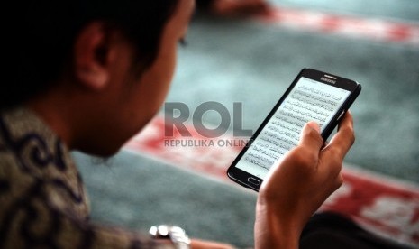 Seorang jamaah membaca ayat Alquran melalui smartphone.