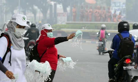   Seorang petugas membagikan masker gratis kepada pengendara yang melintasi di Jambi (ilustrasi)