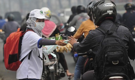   Seorang petugas dari Dinas Kesehatan Pemprov Jambi membagikan masker gratis kepada pengendara yang melintasi  Jalan A. Rahman Saleh, Jambi, Rabu (9/9).  (Antara/Wahyu Putro A)