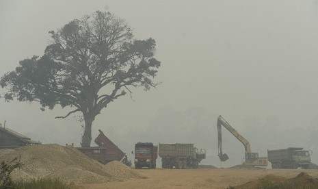   Pekerja mengoperasikan alat berat untuk mengambil pasir dari Sungai Batanghari yang tertutup kabut asap di Jambi, Rabu (9/9).    (Antara/Wahyu Putro A)