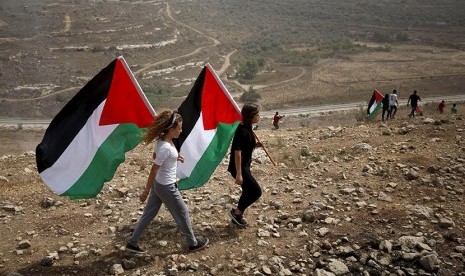 Dua anak membawa bendera Palestina.