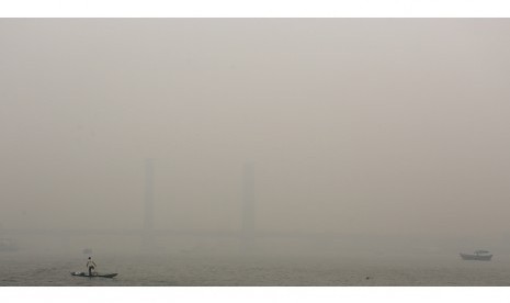  Nelayan mencari ikan diperairan sungai musi dengan latar jembatan Ampera yang tertutup kabut asap, Palembang, Sumsel. Selasa (29/9).   (Antara/Nova Wahyudi)