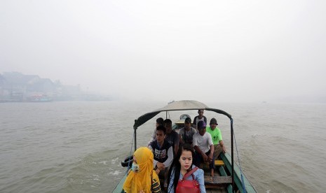   Sejumlah warga menyeberangi sungai Musi dengan menaiki kapal tradisional di perairan sungai musi yang tertutup kabut asap, Palembang, Sumsel. Selasa (29/9).   (Antara/Nova Wahyudi)