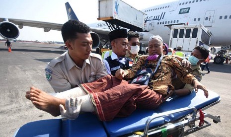 Petugas medis mengangkat Murodi Yahya Kasani (55), jamaah haji kloter pertama embarkasi Surabaya asal Kabupaten Magetan ketika tiba di Bandar Udara Internasional Juanda Surabaya di Sidoarjo, Jawa Timur, Selasa (29/9).  (Antara/M Risyal Hidayat)