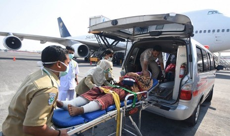 Petugas medis mengangkat Murodi Yahya Kasani (55), jamaah haji kloter pertama embarkasi Surabaya asal Kabupaten Magetan ketika tiba di Bandar Udara Internasional Juanda Surabaya di Sidoarjo, Jawa Timur, Selasa (29/9).  (Antara/M Risyal Hidayat)