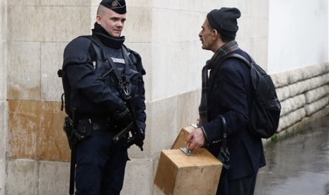  Seorang warga muslim melintasi polisi Prancis yang berjaga di luar masjid kota Paris, Jumat (20/11). (AP/Francois Mori)