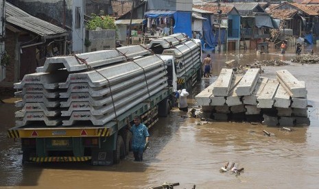 Warga melintas di samping dua buah truk pengangkut turap yang ikut terendam luapan air Sungai Ciliwung di kawasan proyek normalisasi, Kampung Pulo, Jatinegara, Jakarta Timur, Rabu (25/11).  (Antara/Widodo S. Jusuf)