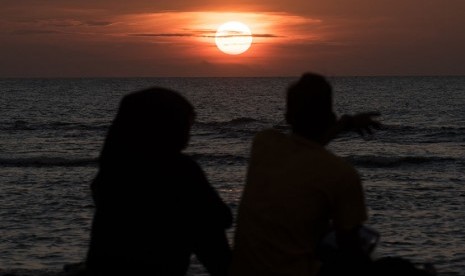 Dua wisatawan menyaksikan matahari terbenam pada penghujung tahun 2015 di pelabuhan Paku, Anyer, Banten, Kamis (31/12). (Antara/M Agung Rajasa)