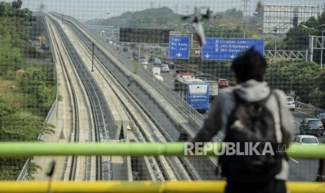 Warga melihat lintasan kereta LRT di kawasan Kampung Makassar, Jakarta, Kamis (3/10).