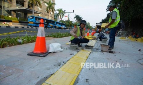 Pekerja menyelesaikan pemasang guiding block atau ubin pengarah bagi penyandang disabilitas 