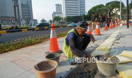 Pekerja menyelesaikan pemasang guiding block atau ubin pengarah bagi penyandang disabilitas di trotoar Bundaran HI, Jakarta, Jumat (11/10/2019).