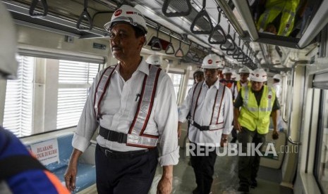 Menteri Koordinator Bidang Kemaritiman Luhut Binsar Panjaitan (kiri) dan Menteri Perhubungan Budi Karya Sumadi (tengah) saat meninjau bagian dalam gerbong LRT di Stasiun Harjamukti, Depok, Jawa Barat, Ahad (13/10).