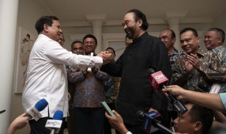 Ketua Umum Partai Gerindra Prabowo Subianto (kiri) berjabat tangan dengan Ketua Umum Partai NasDem Surya Paloh (tengah) usai melakukan pertemuan di kawasan Permata Hijau, Jakarta, Ahad (13/10/2019).