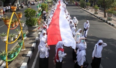 Santri membawa bendera merah putih sepanjang 1.000 meter saat pawai peringatan Hari Santri Nasional di Sidoarjo, Jawa Timur, Ahad (20/10/2019).