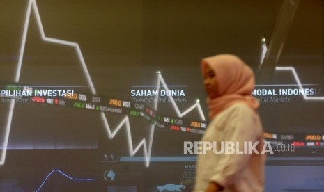 Karyawan melintas di dekat layar pergerakan saham di gedung Bursa Efek Indonesia, Jakarta,Senin (21/10).