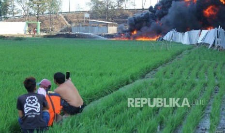 Penduduk mengabadikan kebakaran pipa Pertamina dilokasi proyek pembangunan Kereta Cepat Indonesia-Cina (KCIC), di Kampung Mancong, Kelurahan Melong, Kecamatan Cimahi Selatan, Kota Cimahi, Selasa (22/10).