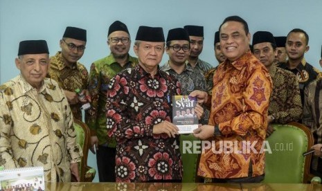 Wakil Ketua Dewan Masjid Indonesia Syafruddin (kanan depan) memberikan buku cinderamata kepada Sekjen MUI Anwar Abbas disaksikan Pemimpin Redaksi Republika Irfan Junaedi (kedua kiri) usai kunjungan ke Kantor MUI, Jakarta, Jumat (1/11).