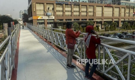 Pejalan kaki melihat pemandangan di jembatan penyeberangan orang (JPO) yang tidak beratap di Jalan Sudirman, Jakarta, Rabu (6/11).