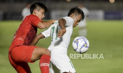 Pesepakbola Timnas Indonesia Mochammad Supriadi (kanan) berebut bola dengan pesepakbola Timnas Hongkong Chan Yu Tung pada pertandingan kualifikasi AFC U-19 di Stadion Madya, Jakarta, Jumat (8/11).