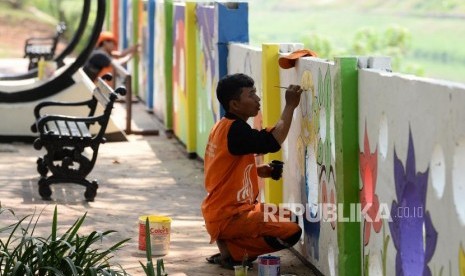 Petugas PPSU kelurahan Pondok Bambu membuat mural di tembok halte sepeda kawasan Banjir Kanal Timur (BKT), Jakarta, Rabu (20/11).