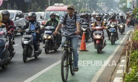 Seorang pesepeda melintasi jalur sepeda diantara para pengendara motor di Jalan RS Fatmawati Raya, Cilandak, Jakarta, Kamis (21/11).