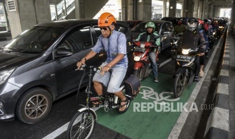 Seorang pesepeda melintasi jalur sepeda diantara para pengendara motor di Jalan RS Fatmawati Raya, Cilandak, Jakarta, Kamis (21/11).