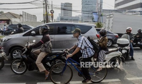 Seorang pesepeda melintasi jalur sepeda diantara para pengendara motor (ilustrasi).