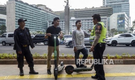 Anggota kepolisian memberi himbauan kepada pengguna skuter listrik yang melintas di jalan MH Thamrin, Jakarta, Ahad (24/11).