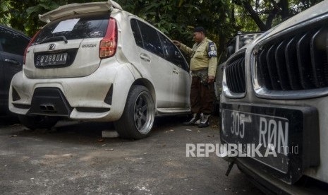 Petugas berada di dekat mobil sitaan aset First Travel di Kejaksaan Negeri Depok, Jawa Barat, beberapa waktu lalu..