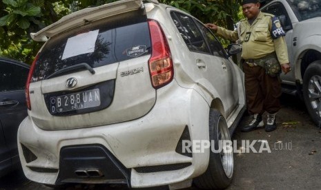 Korban First Travel: Sudah Tujuh Tahun Tidak Ada Kejelasan. Foto:  Petugas berada di dekat mobil sitaan aset First Travel di Kejaksaan Negeri Depok, Jawa Barat, Senin (25/11).