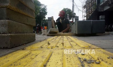 Pekerja memasang guiding block di trotoar Kemang, Jakarta, Rabu (27/11).