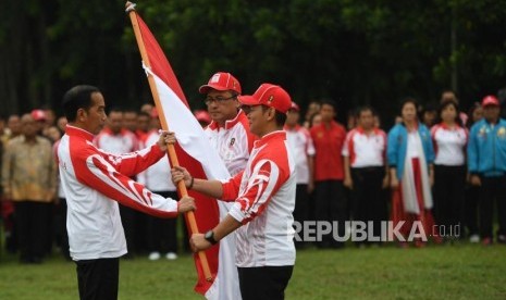 Presiden Joko Widodo (kiri) menyerahkan bendera kepada Ketua Komite Olimpiade Indonesia (KOI) Raja Sapta Oktohari (kanan) disaksikan Ketua Kontingen Indonesia Harry Warganegara (tengah) saat pelepasan atlet untuk SEA Games 2019 di Istana Bogor, Jawa Barat, Rabu (27/11/2019).