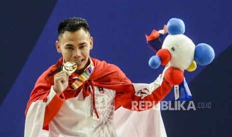 Lifter Putra Indonesia Eko Yuli Irawan menggigit medali emas usai pertandingan cabang olahraga angkat besi kategori putra 61 kilogram di RSMC Ninoy Aquino Stadium, Manila, Filipina, Senin (2/12).