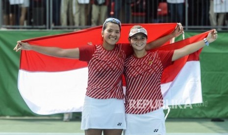 Petenis Indonesia Beatrice Gumulya dan Jessy Priskilia Rompies membentangkan bendera merah putih usai mengalahkan petenis Thailand Peangtarn Plipuech dan Tamarine Tanasugarn pada pertandingan final tenis kategori ganda putri di RMSC Tennis Court, Manila, Filipina, Sabtu (7/12).