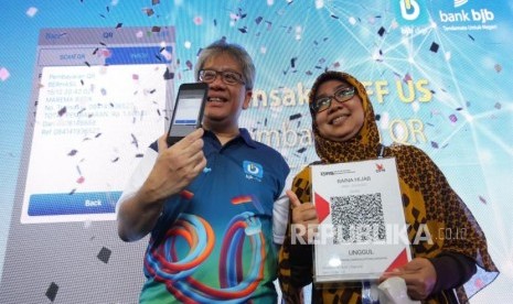 Direktur Utama Bank BJB Yuddy Renaldi (kiri) bersama perwakilan pedagang melakukan transaksi pembayaran digital saat piloting penggunaan Quick Response Code Indonesian Standard (QRIS), di Pasar Baru, Kota Bandung, belum lama ini. 