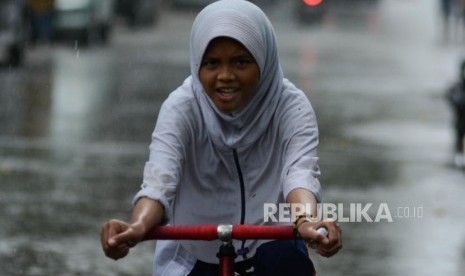 Anak bermain saat hujan lebat. BMKG Kelas I Juanda memprediksi hujan dan angin kencang akan melanda Jatim. Ilustrasi.