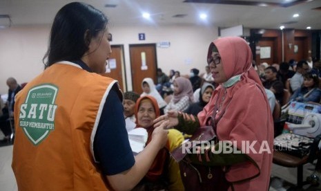 Petugas BPJS Kesehatan Siap Membantu (BPJS SATU) memberikan informasi kepada calon pasien RS Jantung Harapan Kita, Jakarta, Kamis (19/12).