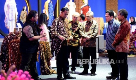 Presiden Joko Widodo mencoba batik didampingi Menteri Koperasi Usaha Kecil & Menengah Teten Masduki (empat kiri), Direktur Utama Bank BRI Sunarso (kanan),Menteri BUMN Erick Thohir (dua kanan) dan Ketua Dewan Komisioner OJK Wimboh Santoso (tiga kanan) saat meninjau stand pada UMKM Export BRILian Preneur 2019 di Jakarta Convention Center, Jumat (20/12).