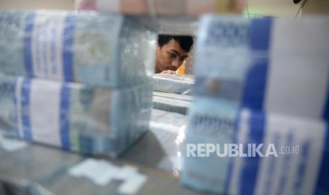 Petugas menata tumpukan uang di cash pooling salah satu bank di Jakarta. LPS mencatat pertumbuhan tabungan Rp 500 juta melambat.