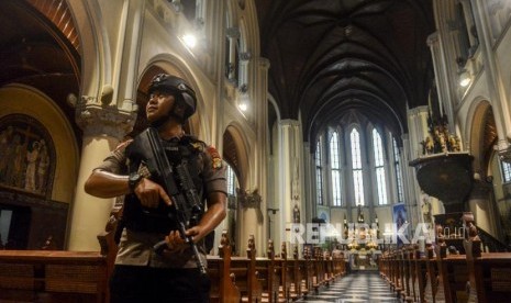 Gereja Katedral Gelar Tiga Misa Malam Natal. Foto: Petugas kepolisian melakukan penjagaan di Gereja Katedral, Jakarta, Senin (23/12).